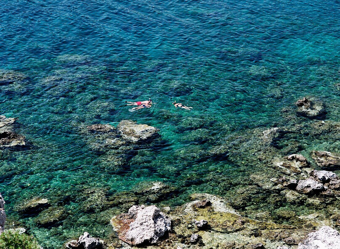 Father And Two Daughters Snorkelling In The Sea Beside Ladiko Beach