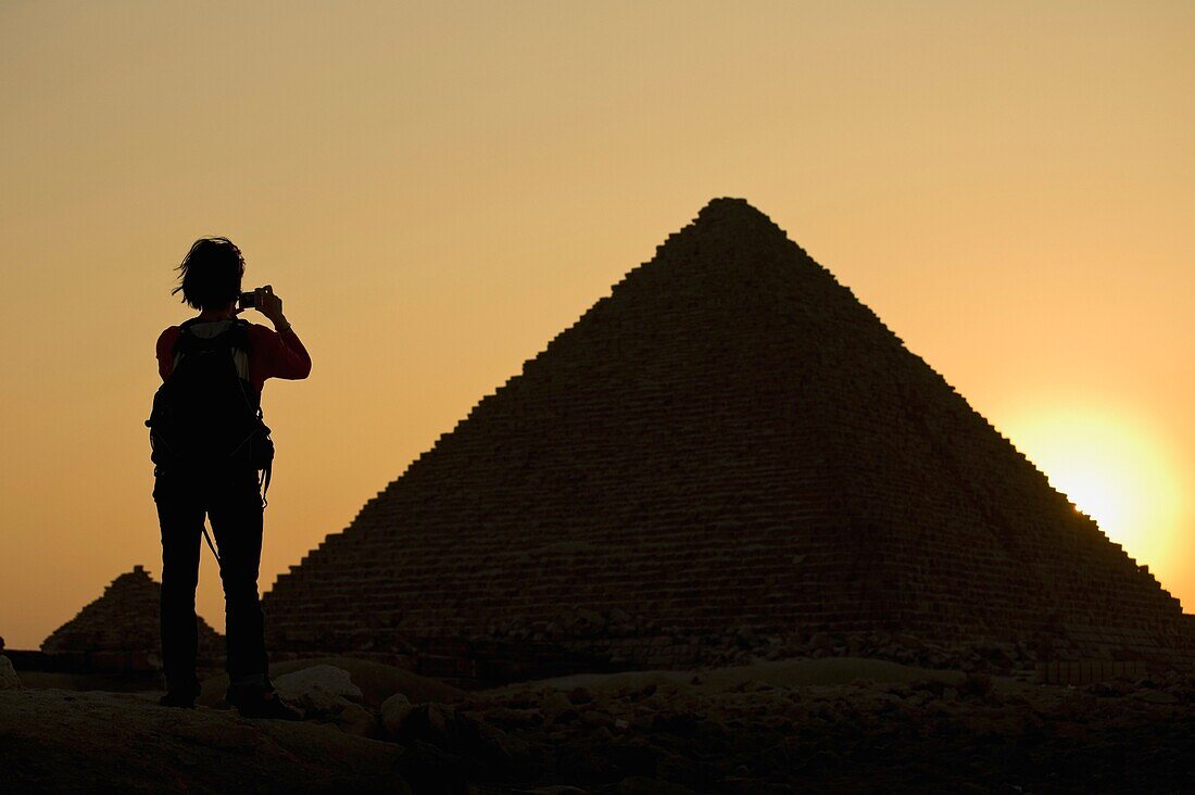 Silhouette einer Frau beim Fotografieren der Pyramiden in der Abenddämmerung