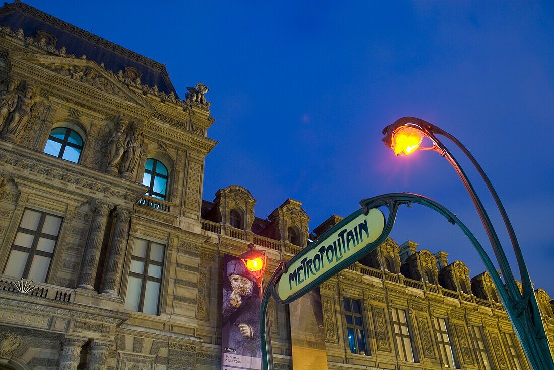 Metro-Zeichen und der Louvre in der Abenddämmerung.