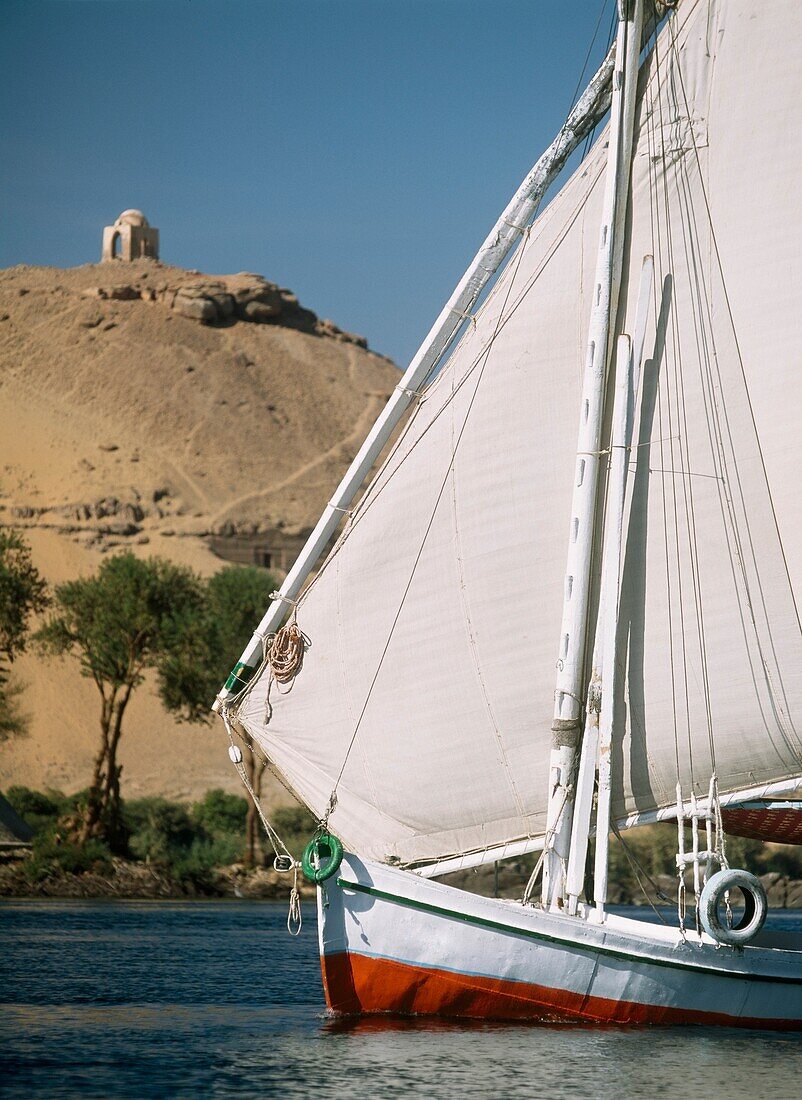 Feluke auf dem Nil mit Gräbern von Adligen und Qubbet El-Hawa dahinter
