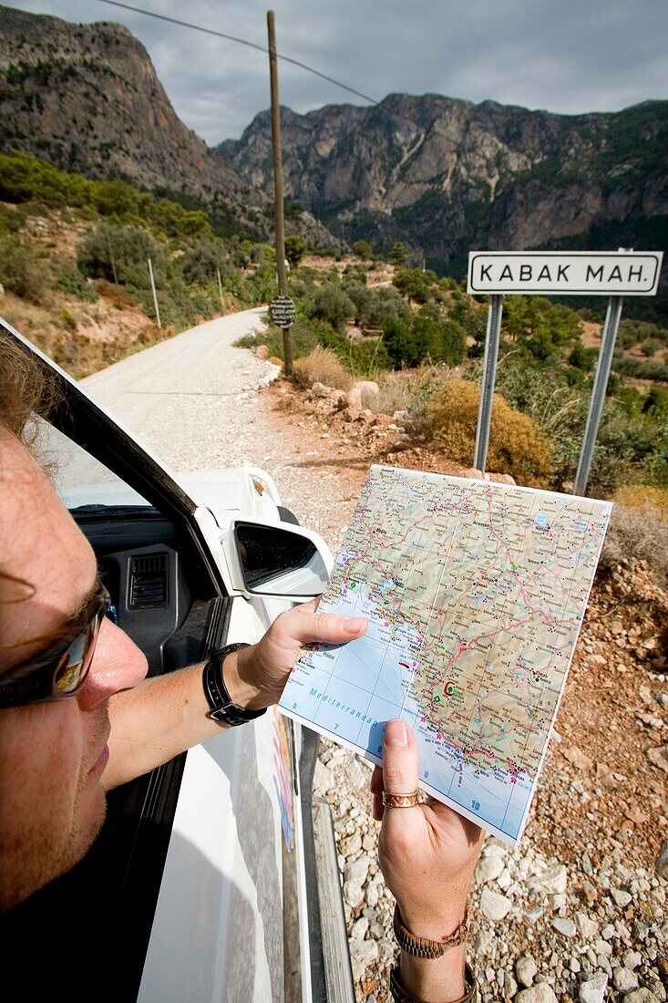 Tourist mit Sonnenbrille im Auto beim Überprüfen der Karte