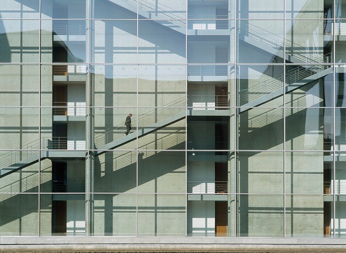Mann geht Treppe hoch in modernem Bürogebäude an der Spree