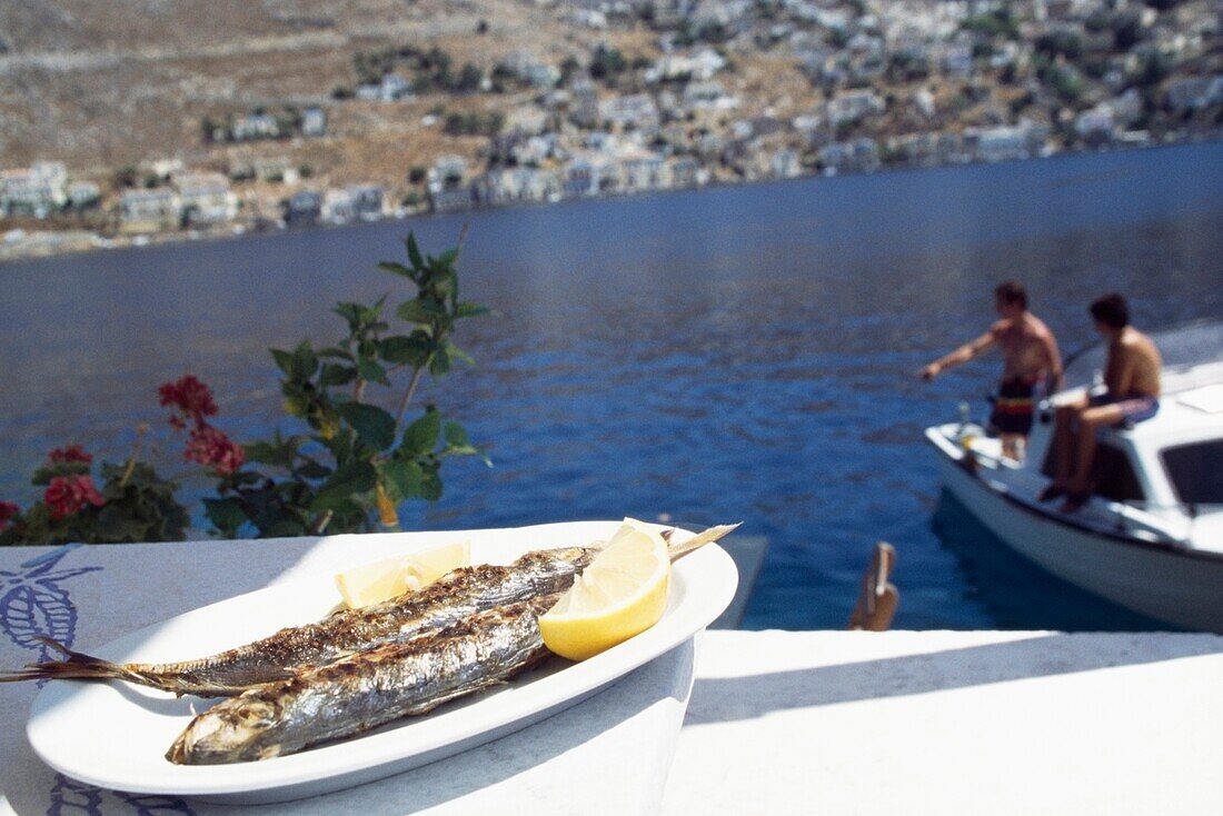 Essen auf dem Teller und Fischer beim Fischen im Hintergrund
