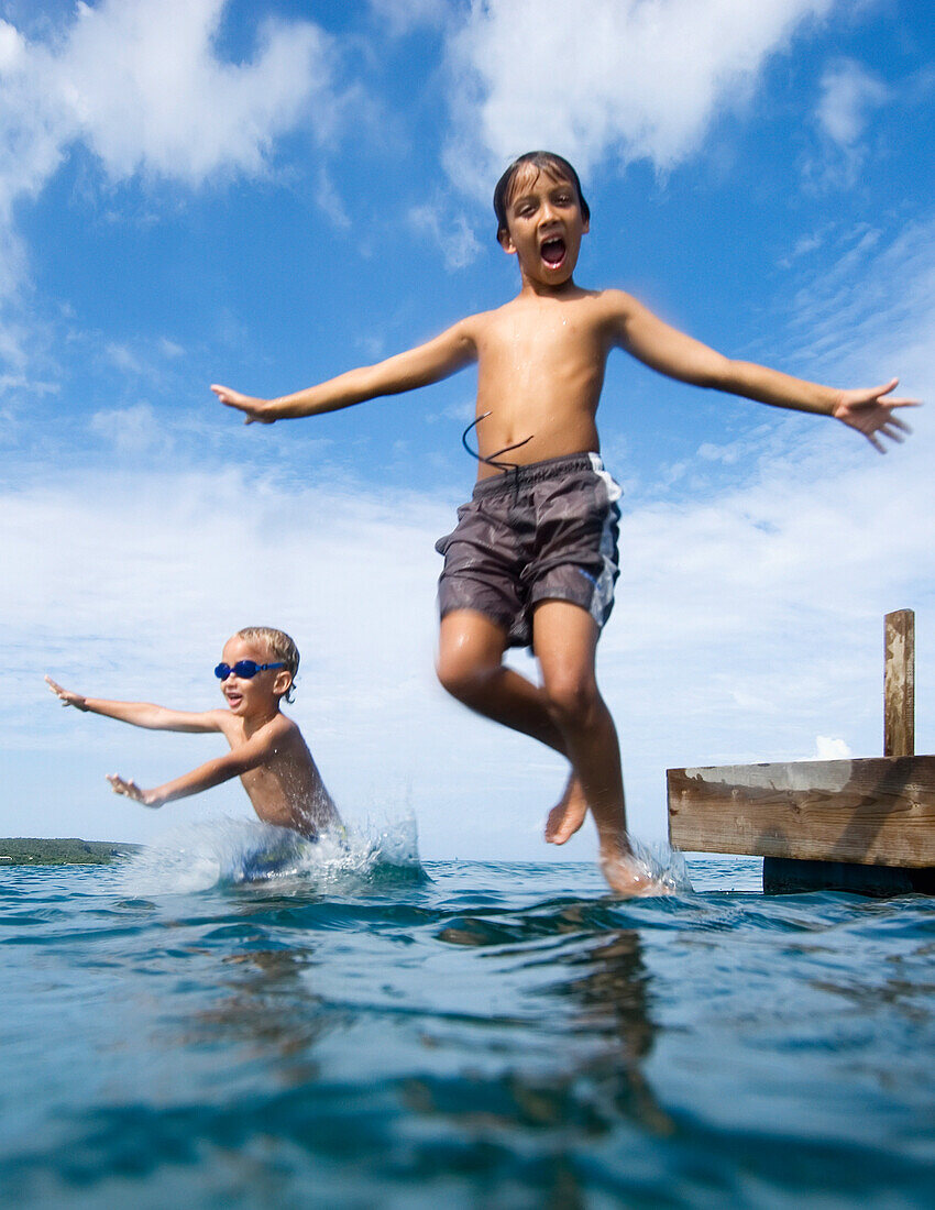 Zwei Kinder springen vom Pier in den Ozean
