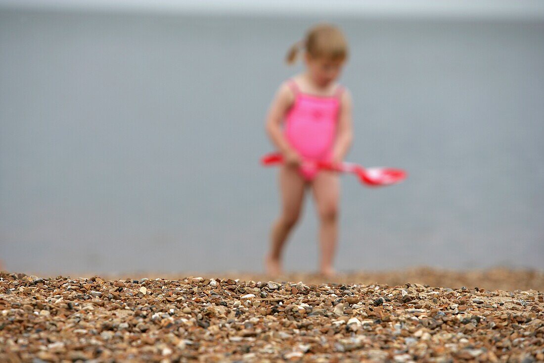 Kind im rosa Badeanzug beim Spielen am Strand