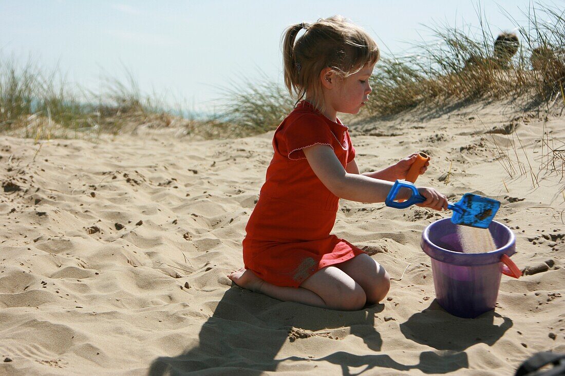 Girl Playing With Bucket And Spade On Dune