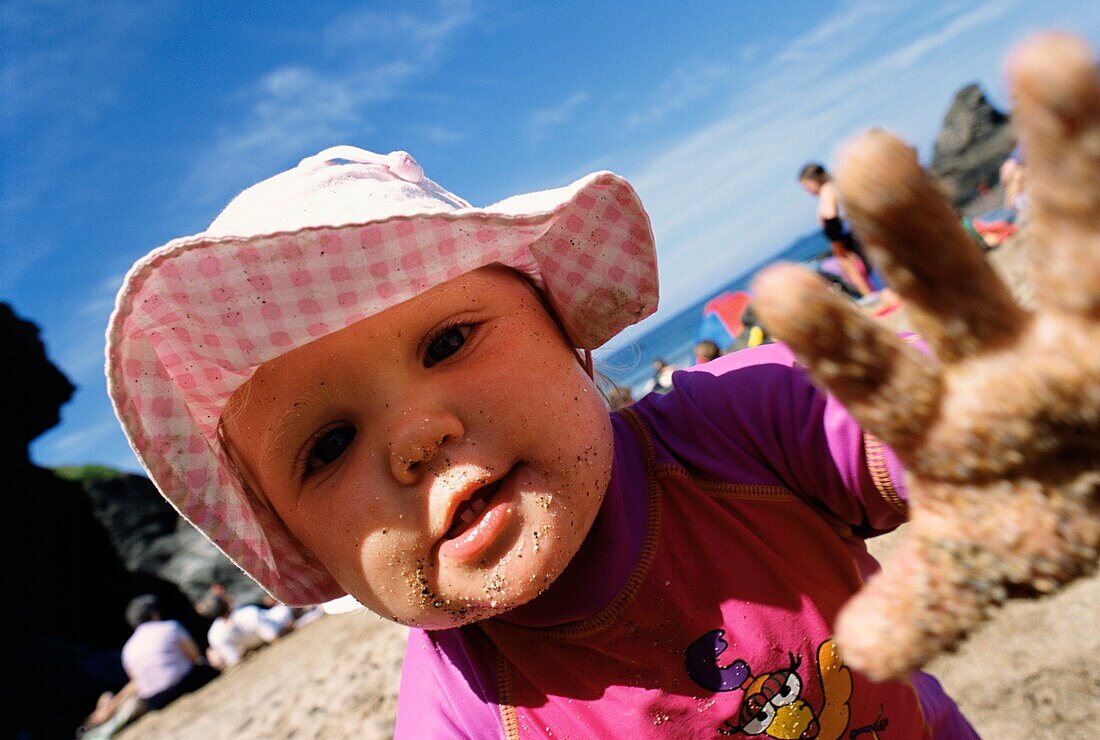 Baby Girl With Sandy Hand On The Beach
