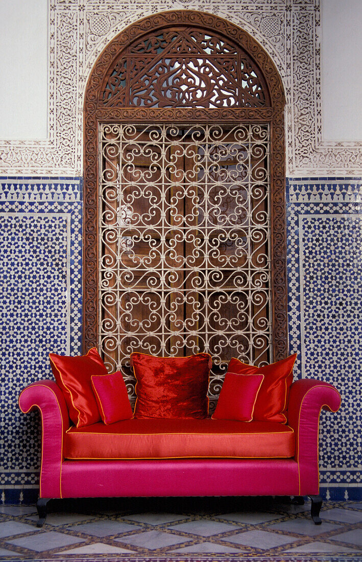Rosa und rotes Sofa vor einer gewölbten Nische und einem Fenster