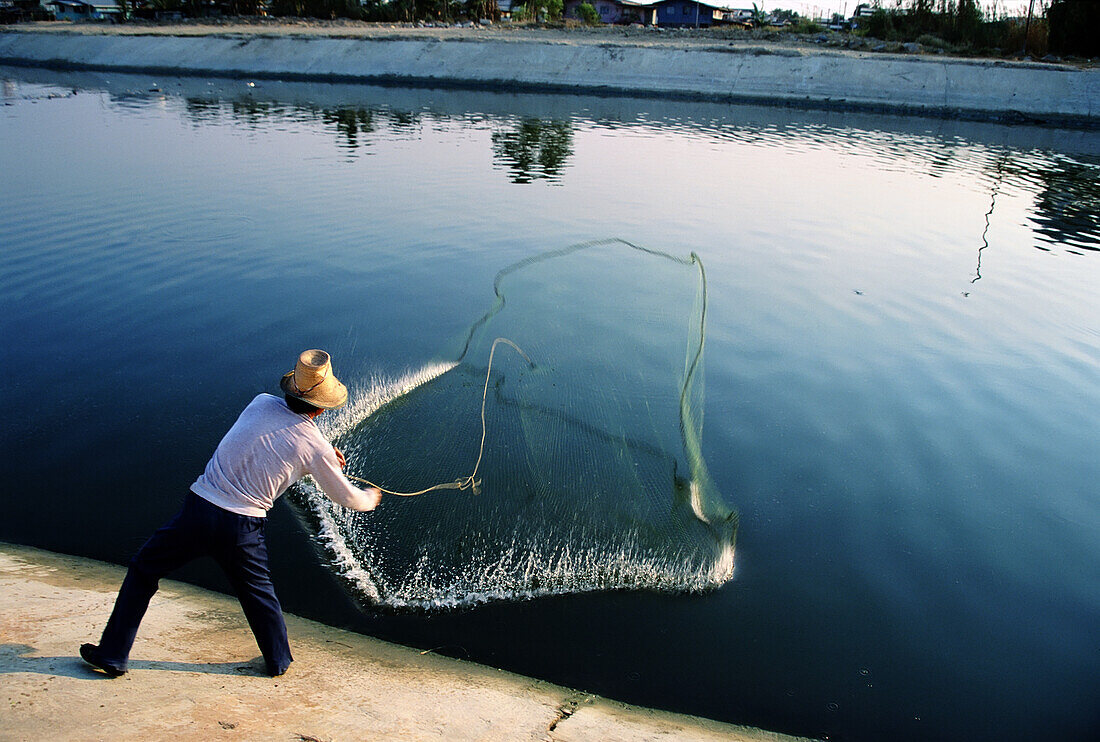 Mann, der ein Fischernetz in einen Kanal wirft