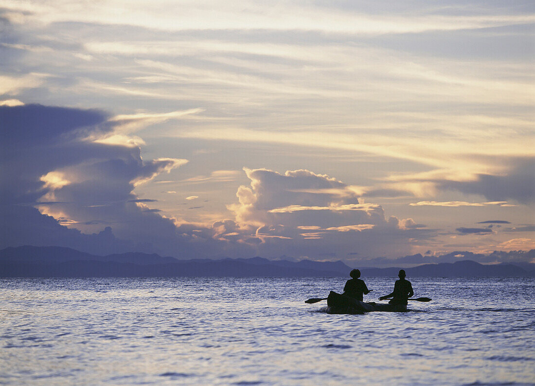 Fischer, die in der Abenddämmerung an der Insel Domwe vorbeiziehen