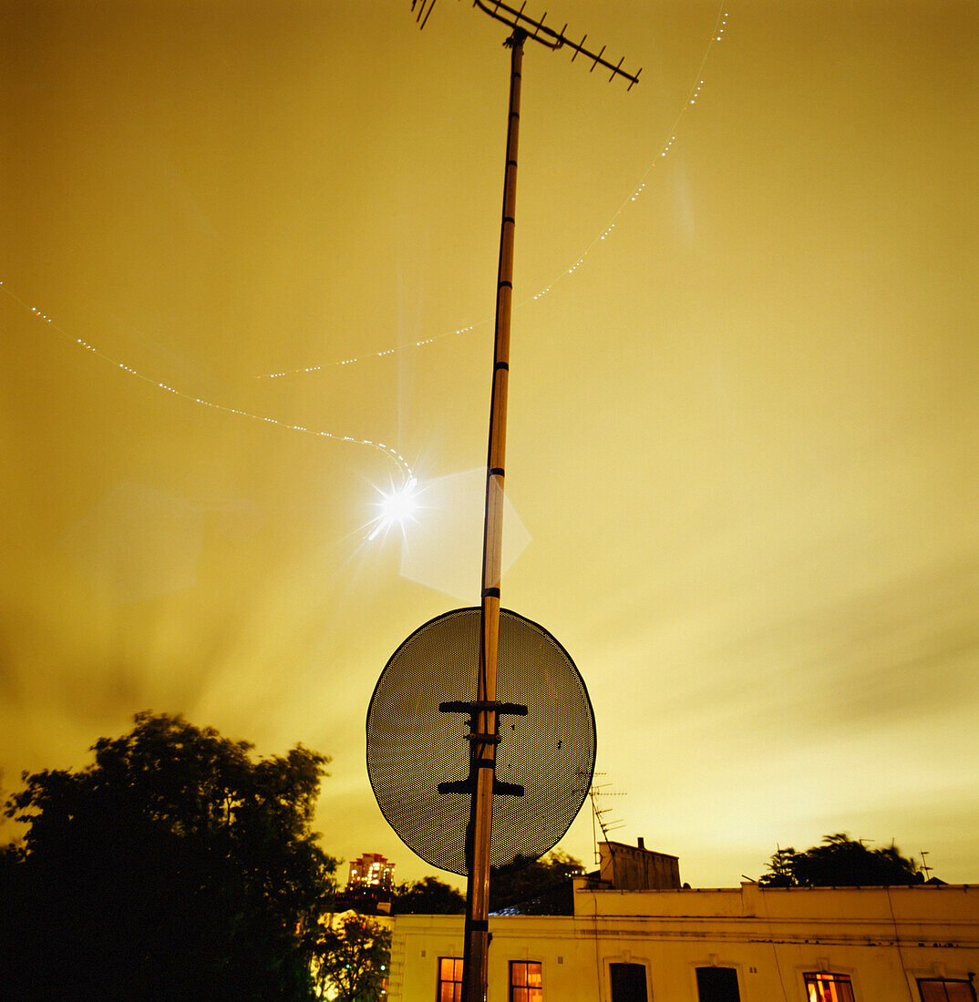 Lichtspuren im nächtlichen Himmel über Häusern und Straßenschildern