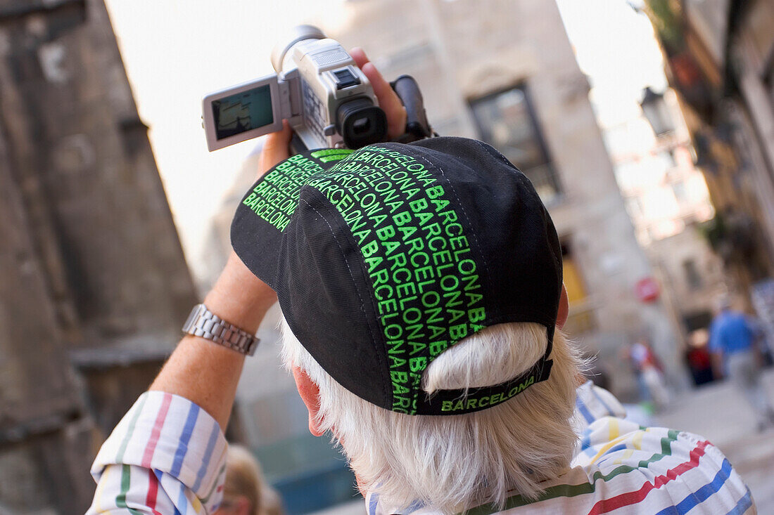 Älterer männlicher Tourist mit Souvenirhut, der die Kathedrale filmt