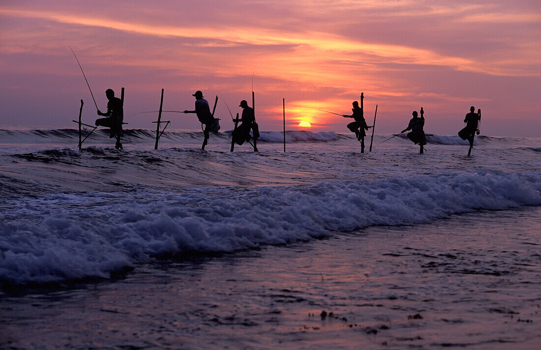 Stilt Fishermen Silhouetted At Sunset