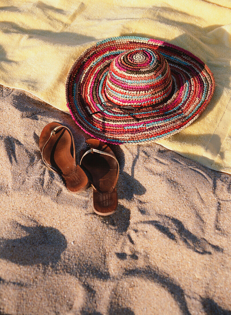 Sonnenhut und Flip Flops auf einem Handtuch am Strand, Nahaufnahme