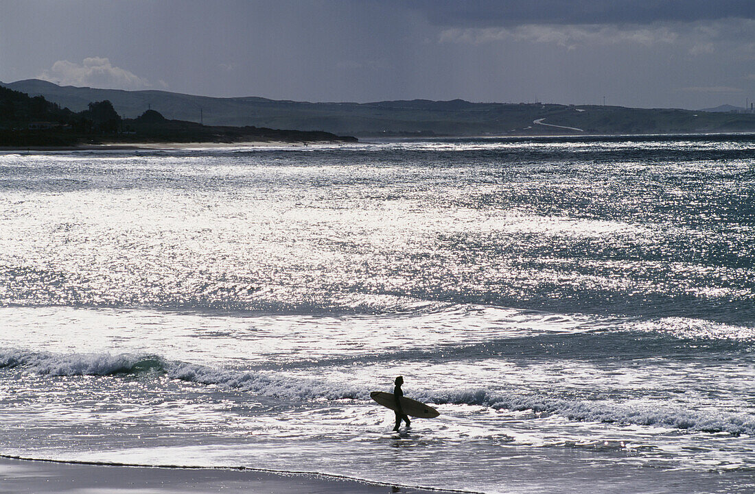 Silhouetted Surfer Walking Into Ocean
