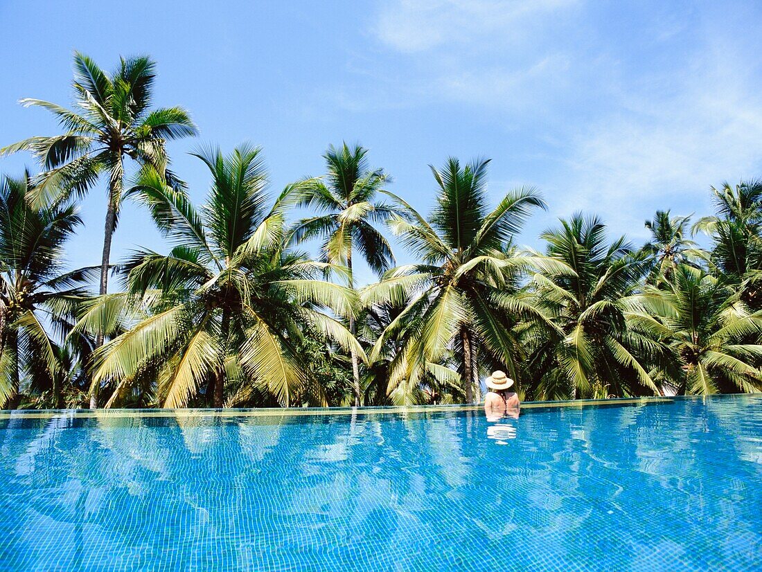 Frau im Infinity-Pool und Palmen