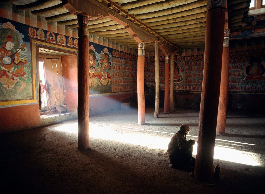 Indien, Ladakh, Alter Mann betet im Tsemo-Kloster mit Lichtstrahl, der durch die Türöffnung fällt; Leh