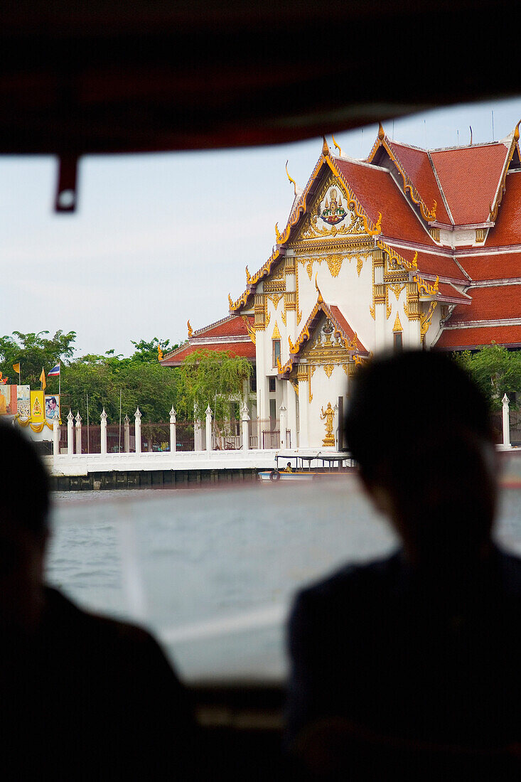 Touristen auf einem Boot auf dem Chao Phraya Fluss, vorbei am Grand Palace