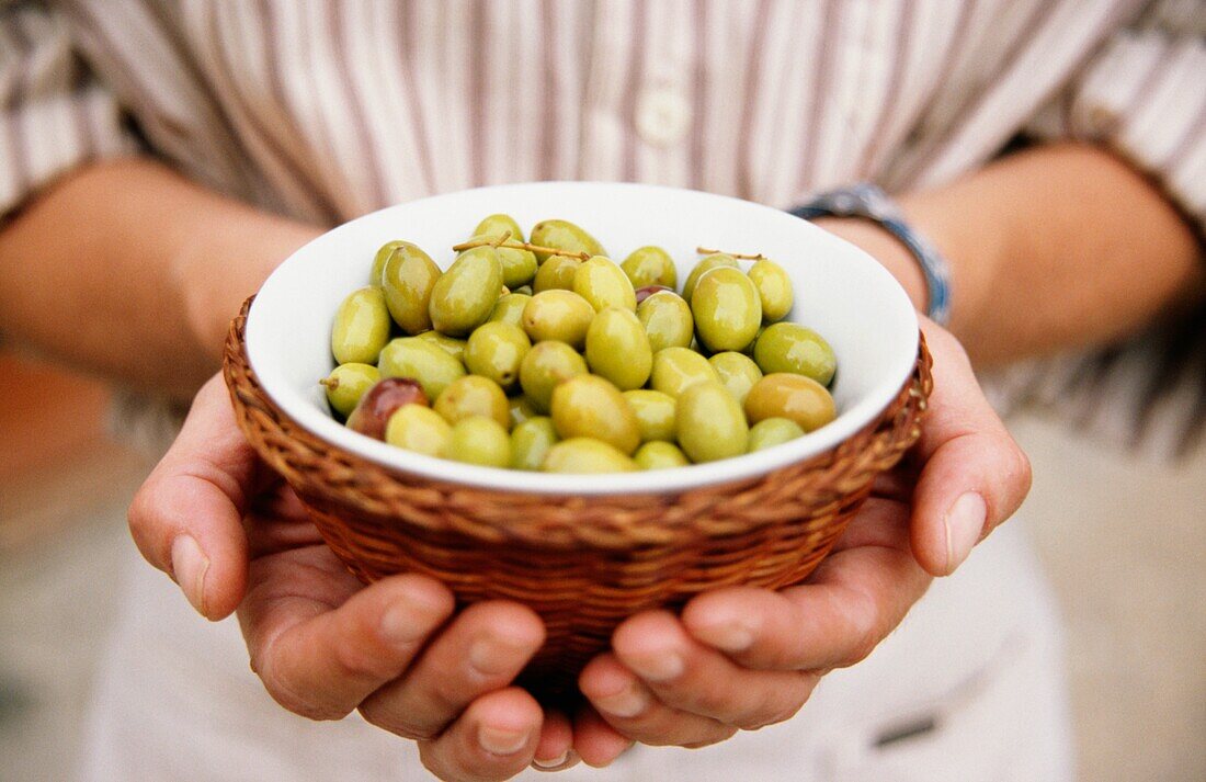 Man Holding A Bowl Of Green Olives