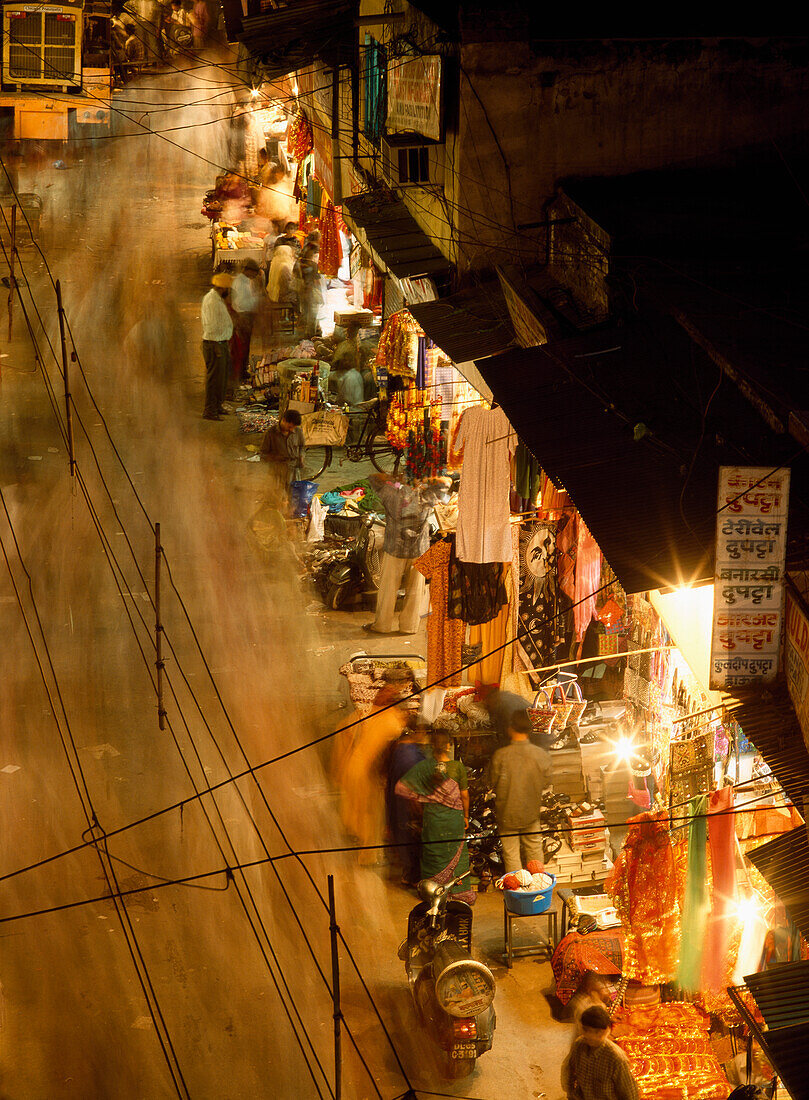 Luftaufnahme von Menschen beim Einkaufen und Spazierengehen bei Nacht, unscharfe Bewegung