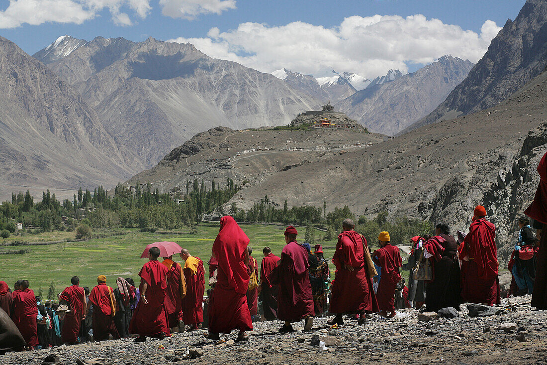 Buddhistische Mönche wandern in einer Menschenmenge mit schneebedeckten Gipfeln