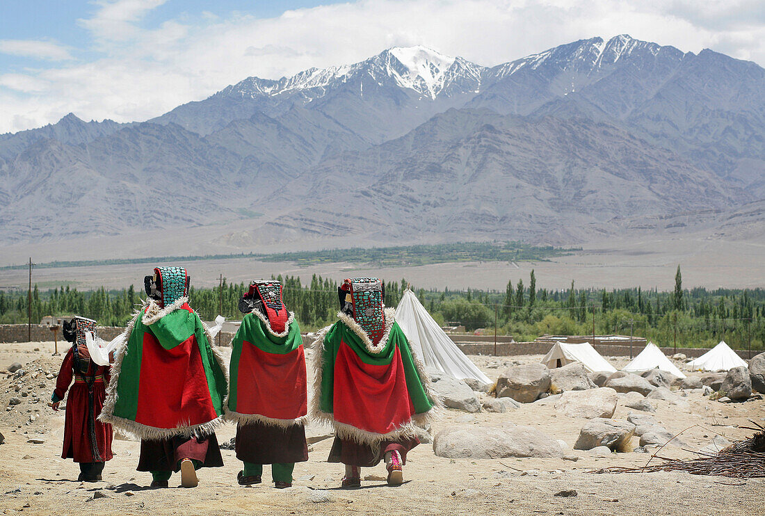 Ladakhi Women In Traditional Dress And Hats Walking Under Snowcapped Mountains