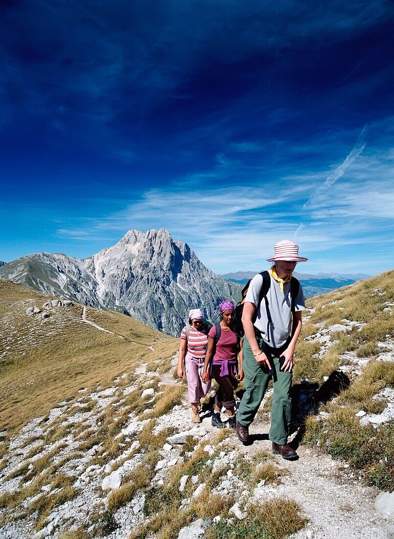 Three Women Walking Along Ridge In Front Of Corno Grande In The Campo Imperatore