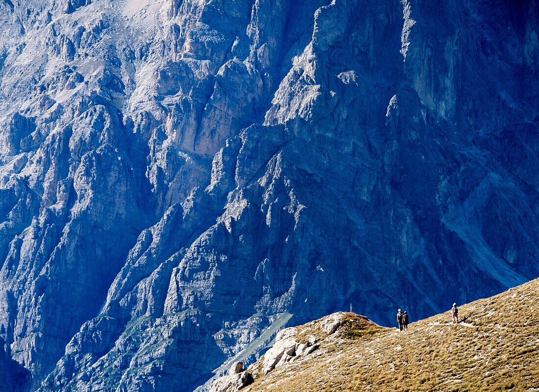 Drei Frauen gehen entlang des Bergrückens vor der Südostwand des Corno Grande