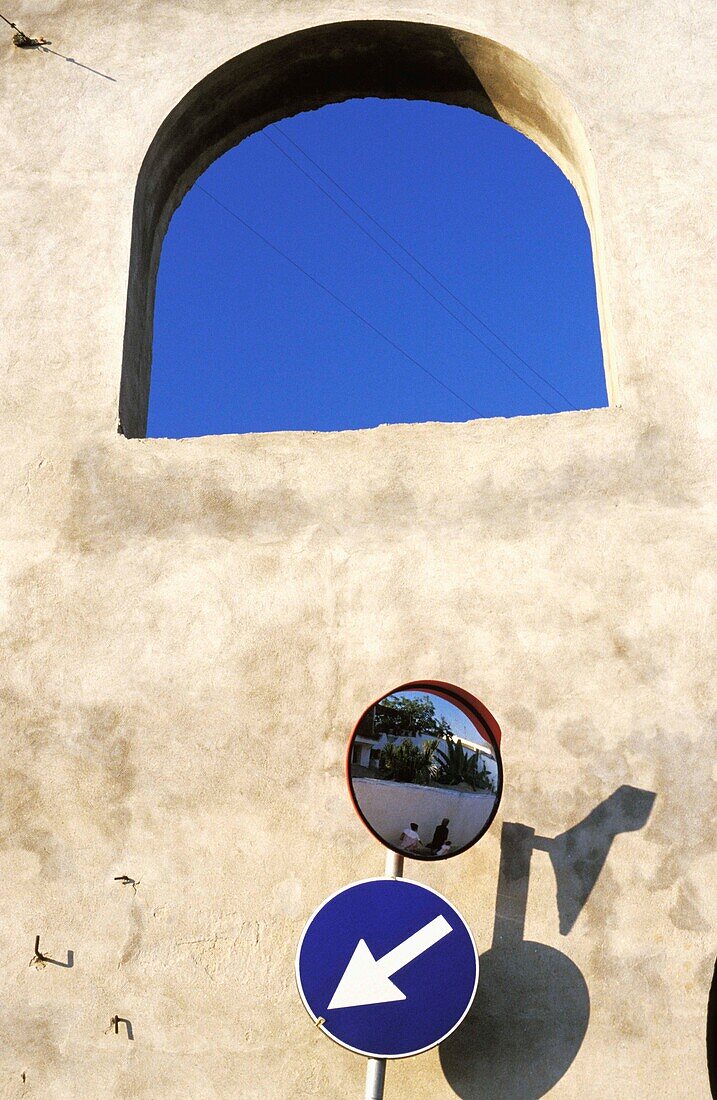 Street Sign And Mirror In Front Of Wall