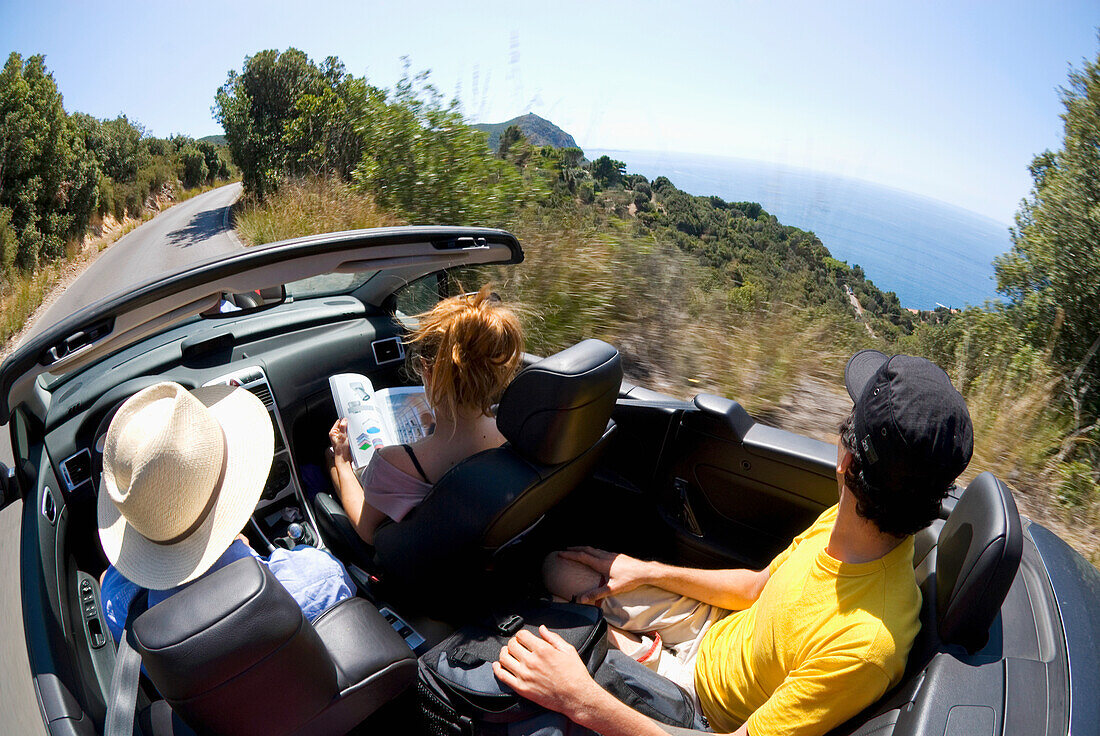 Three People In Convertible Driving By Sea