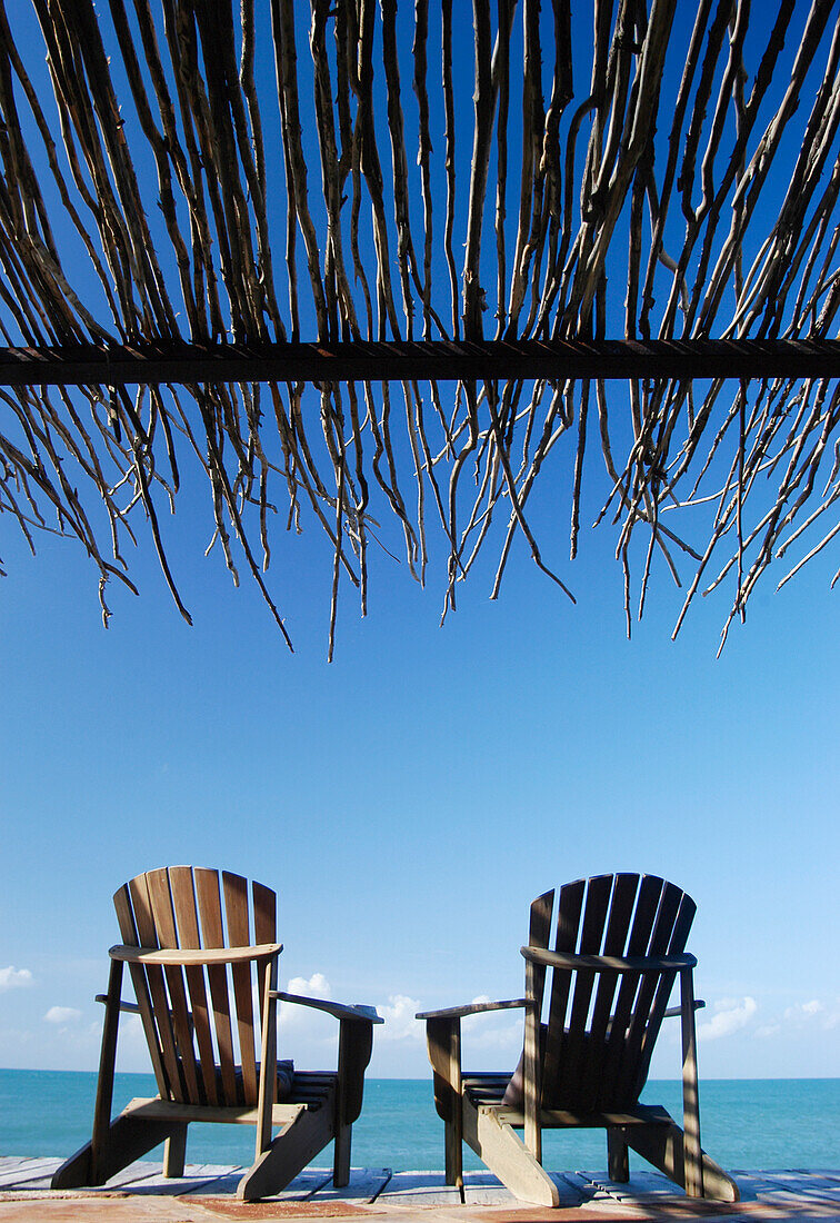 Zwei Stühle auf einer Veranda am Meer