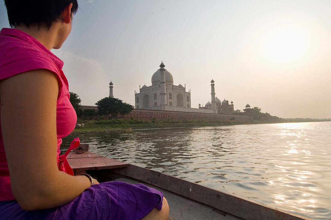 Tourist auf einem Boot, das den Yamuna-Fluss in der Abenddämmerung neben dem Taj Mahal überquert