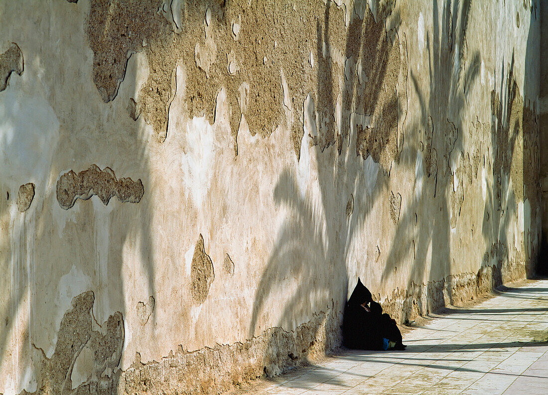 Lady Wearing Djelleba Sitting In Shade By Wall
