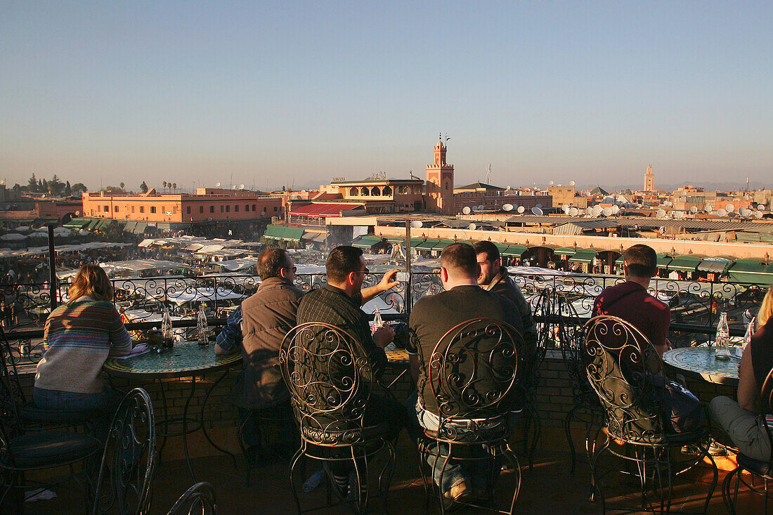 Tourists Drinking Tea On The Balcony Of Cafe Overlooking Djemaa El Fna Night Market.