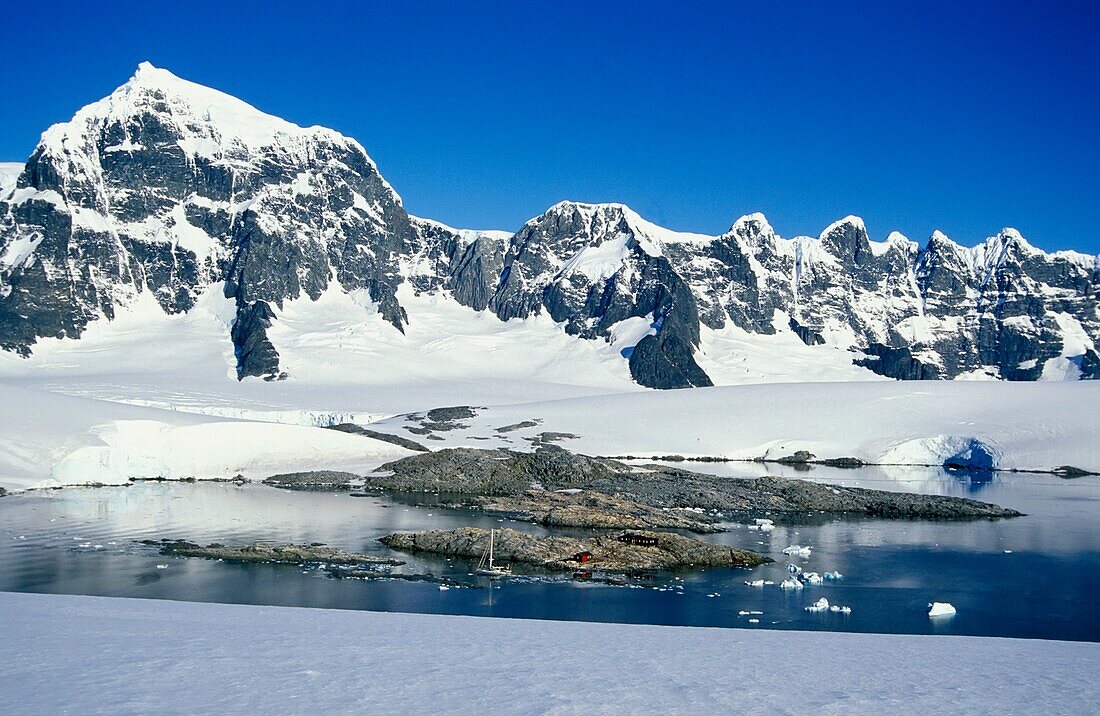 Winzige Hütte und Boot und große Berge mit Schnee