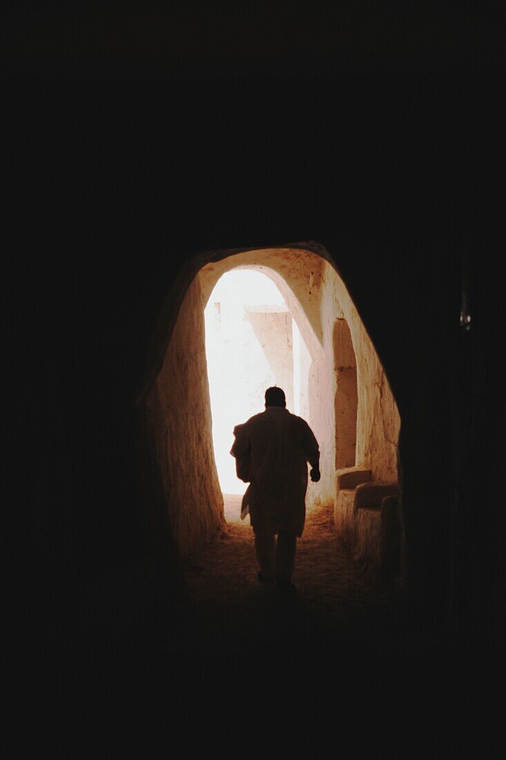 View Of Man Walking Down Alleyway With Archway