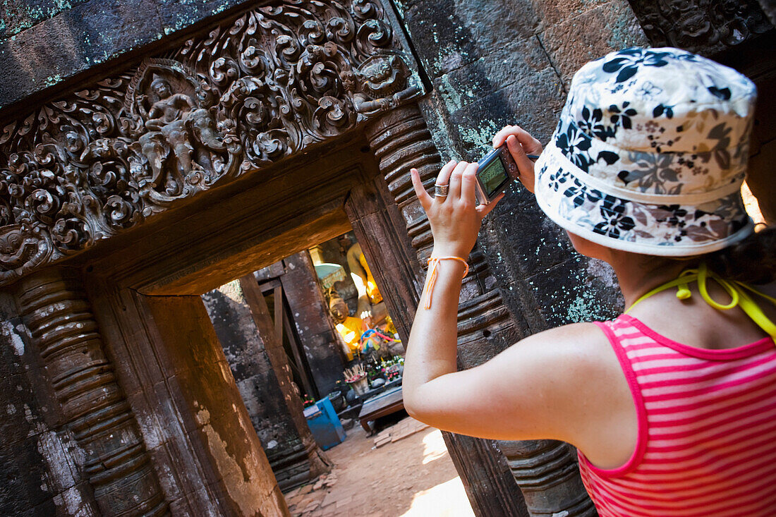 Junge Frau macht Fotos von den Ruinen des Wat Phu.
