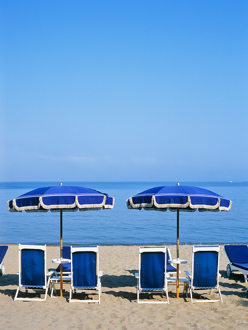 Liegestühle und Sonnenschirme am Strand