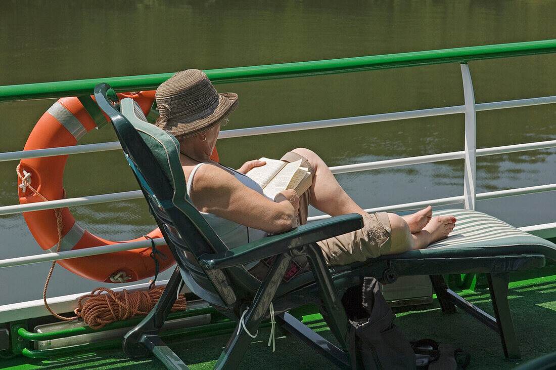 Eine Frau auf einer Sonnenliege liest ein Buch auf einer Flusskreuzfahrt