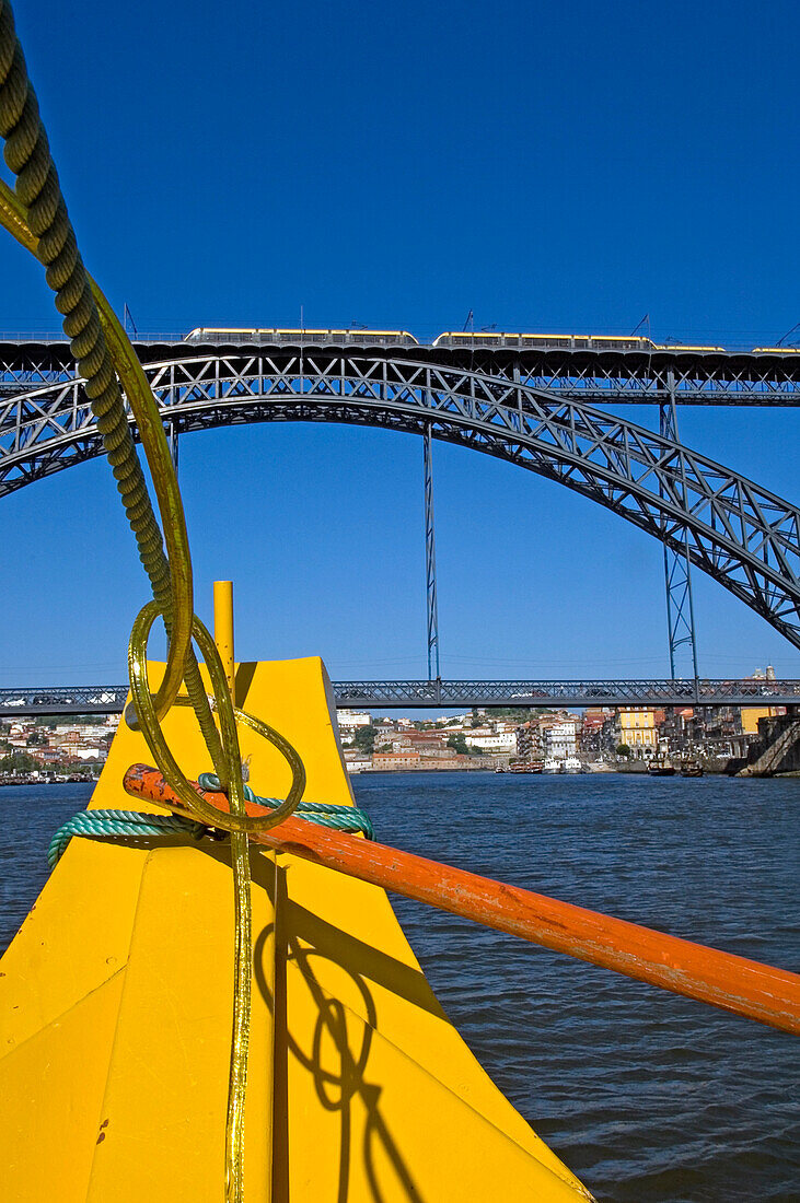 Ein gelbes Kreuzfahrtschiff auf dem Douro, das unter einer Brücke hindurchfährt