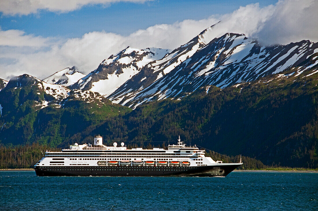 Ein Kreuzfahrtschiff fährt durch die Kachemak Bay und verlässt den Hafen auf der Nehrung von Homer vor dem Hintergrund der schneebedeckten Kenai-Berge im Kachemak Bay State Park, Süd-Zentral-Alaska, Sommer