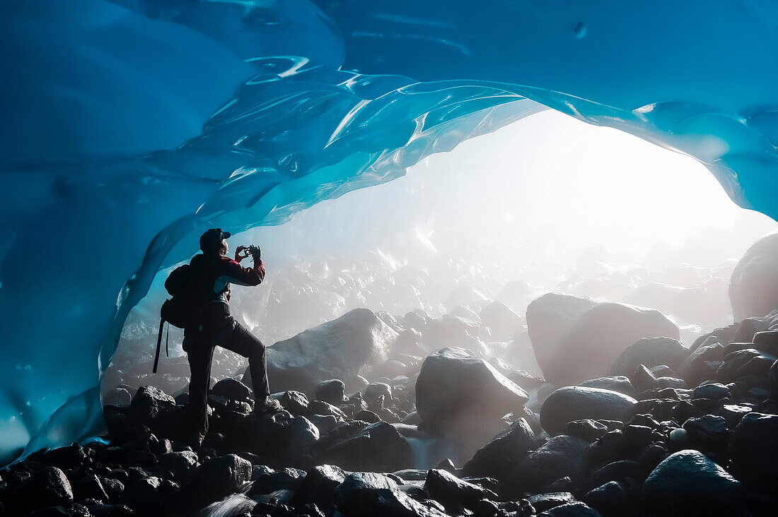 Ein Wanderer fotografiert den Eingang einer Eishöhle von der Innenseite des Mendenhall-Gletschers, Juneau, Südost-Alaska, Sommer
