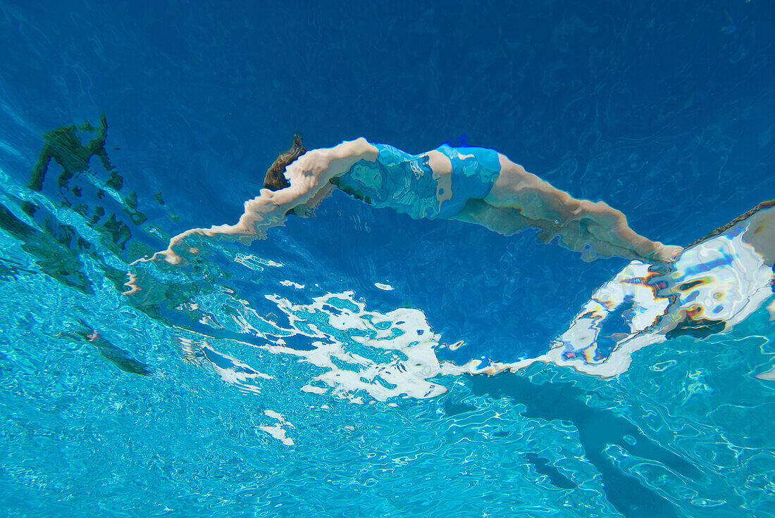 Unterwasseransicht einer Frau, die in einen Pool taucht