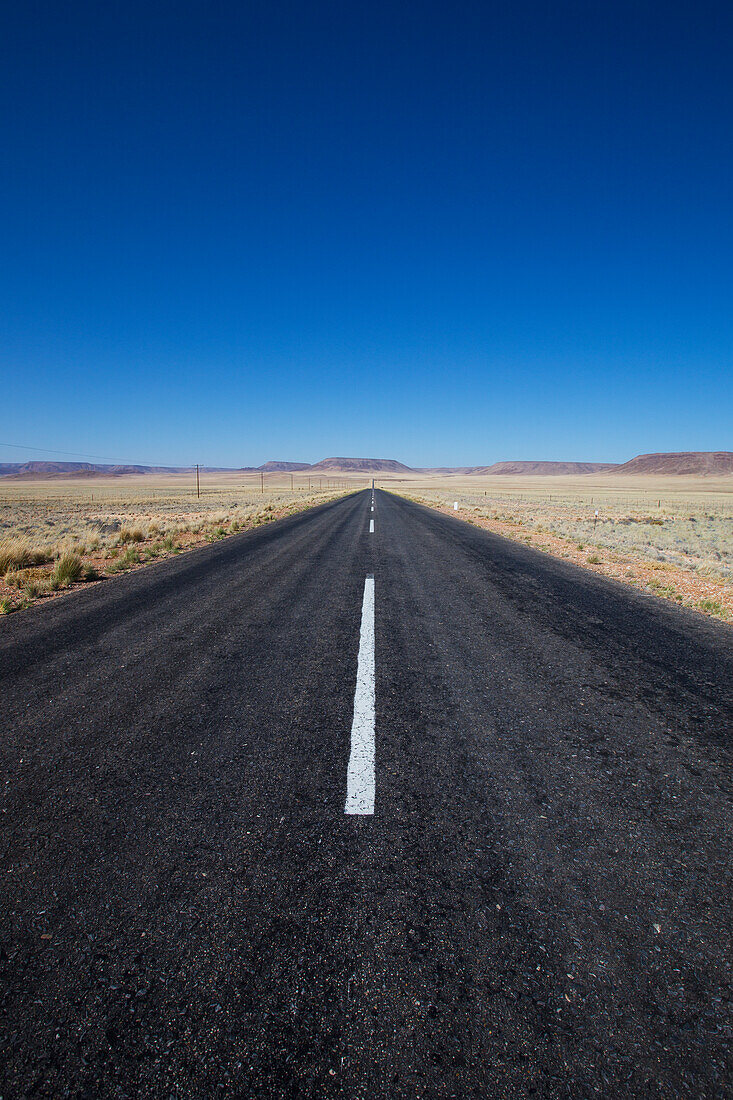 Gepflasterte Straße in einer ländlichen Gegend mit blauem Himmel; Namibia