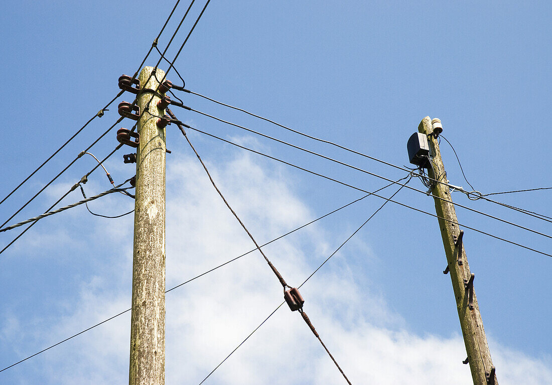 Telefon- und Stromkabel vor blauem Himmel und Wolken; England