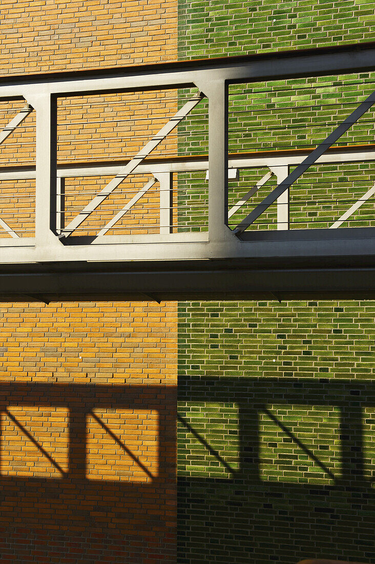 Ein erhöhter Gehweg mit einer Backsteinmauer in zwei Farben, braun und grün; Hamburg, Deutschland