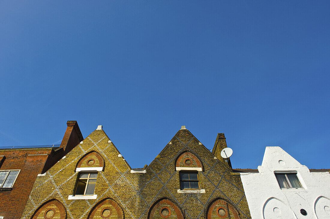 Facade Of Residential Buildings With Peaked Rooflines And A Blue Sky, Camden; London, England