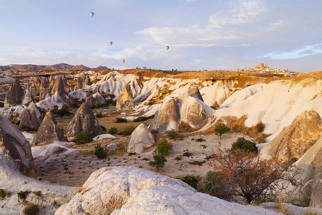 Heißluftballons über einer Landschaft mit zerklüfteten Felsformationen und Klippen; Goreme, Kappadokien, Türkei