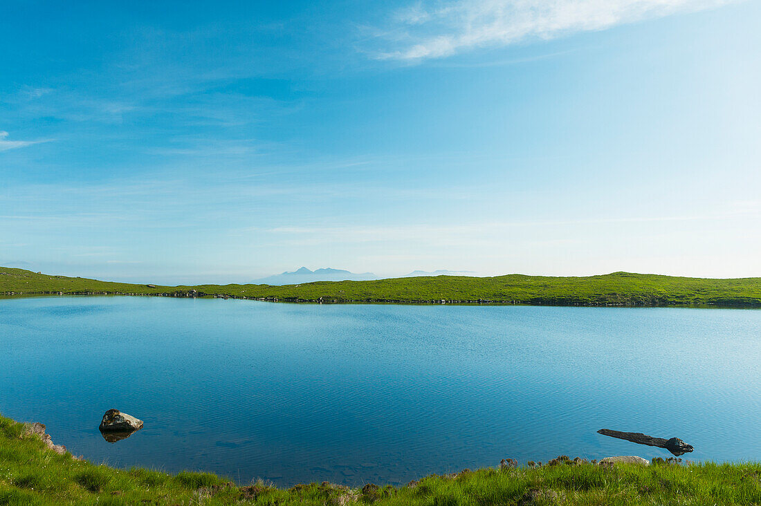 Blick über einen kleinen, ruhigen See hinüber zur Isle of Rum in der Ferne; Isle of Skye, Schottland