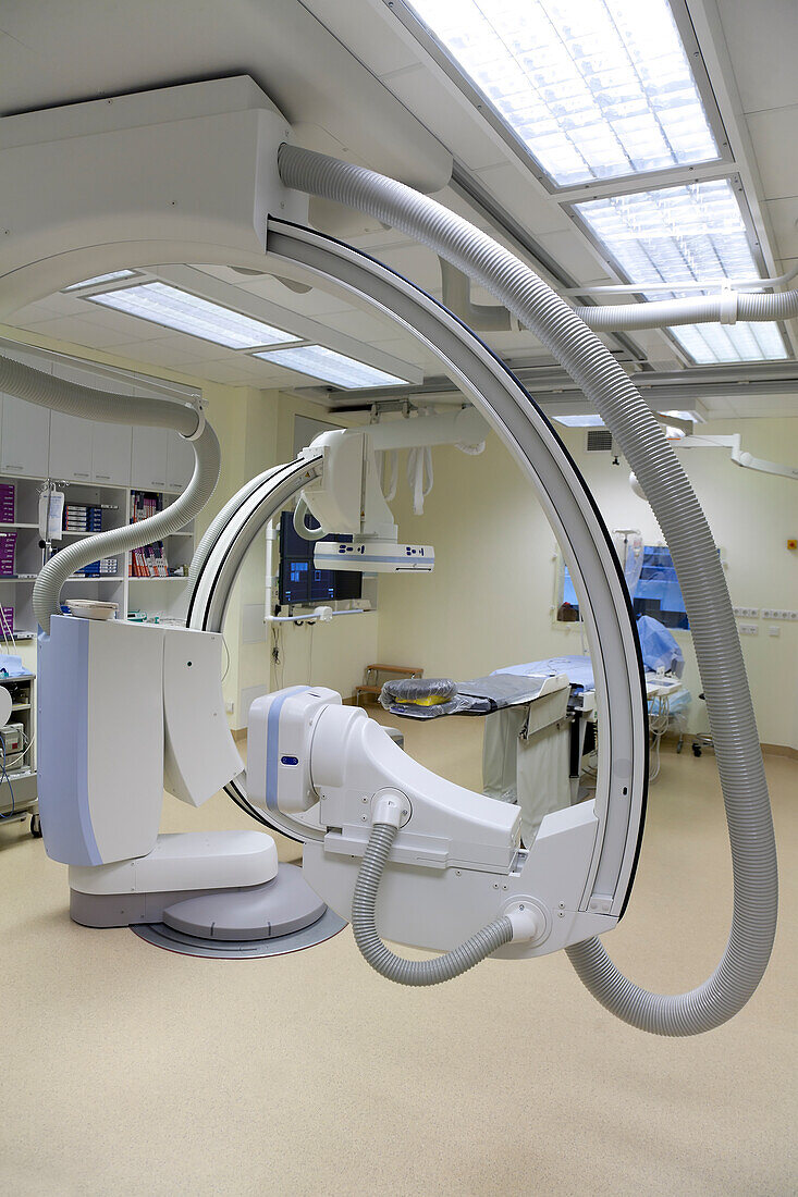 Ein modernes Krankenhauszimmer, eine große tragbare mobile Scannermaschine mit gebogenen Armen, ein mobiler Scanner und eine Krankenhausliege oder ein Krankenhausbett.